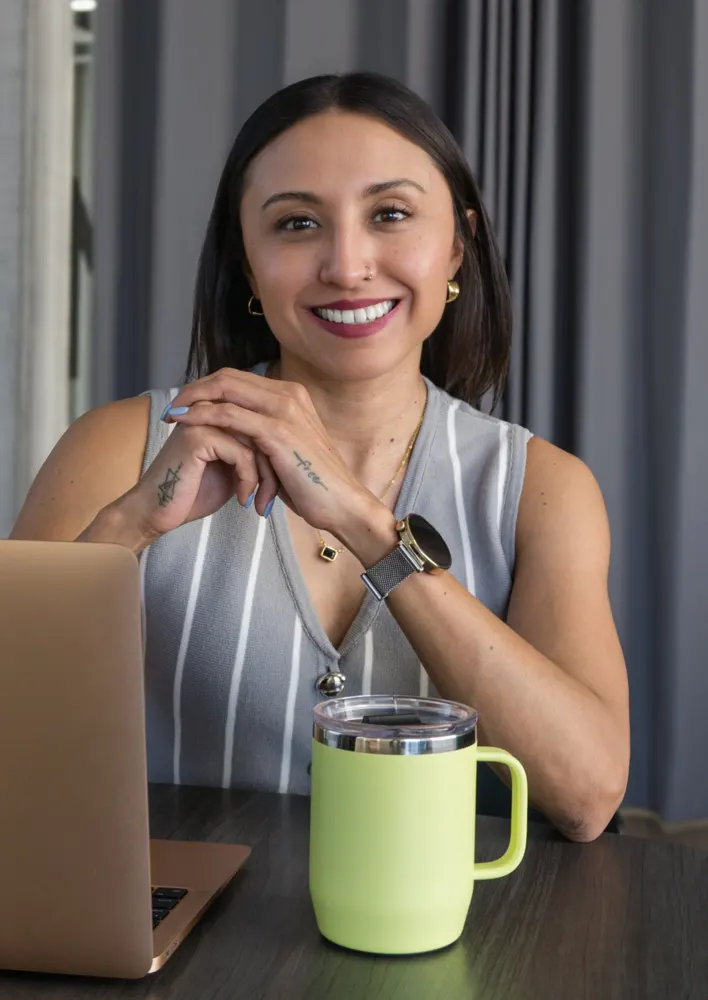 Ogui Magaña, asesora de seguros y coach de bienestar financiero en Monterrey, sonriendo en su escritorio